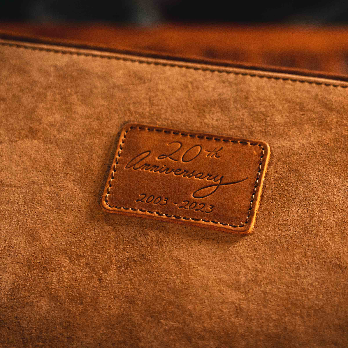 Leather Desk Box, close-up of the stitched leather patch embossed 20th Anniversary 2003-2023 on suede lining