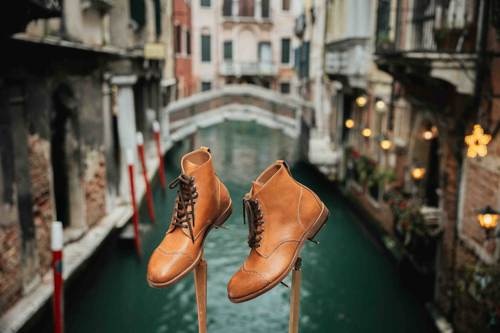 Pair of high quality English tan leather Officer's Boots on wooden stands above a Venice canal