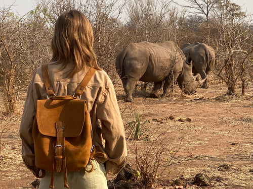 12" Drawstring Backpack in Tobacco, worn by a woman watching two rhinos in the African bush