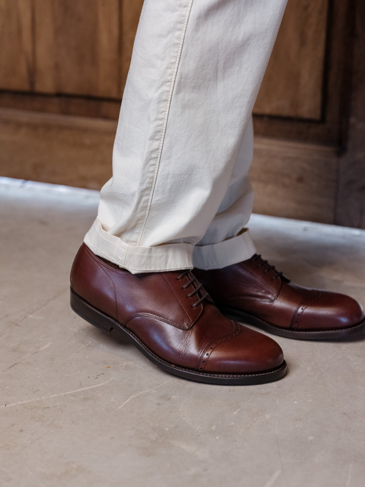Toe Cap Shoes in Dark Oak, side view of the pair worn with cuffed cream trousers