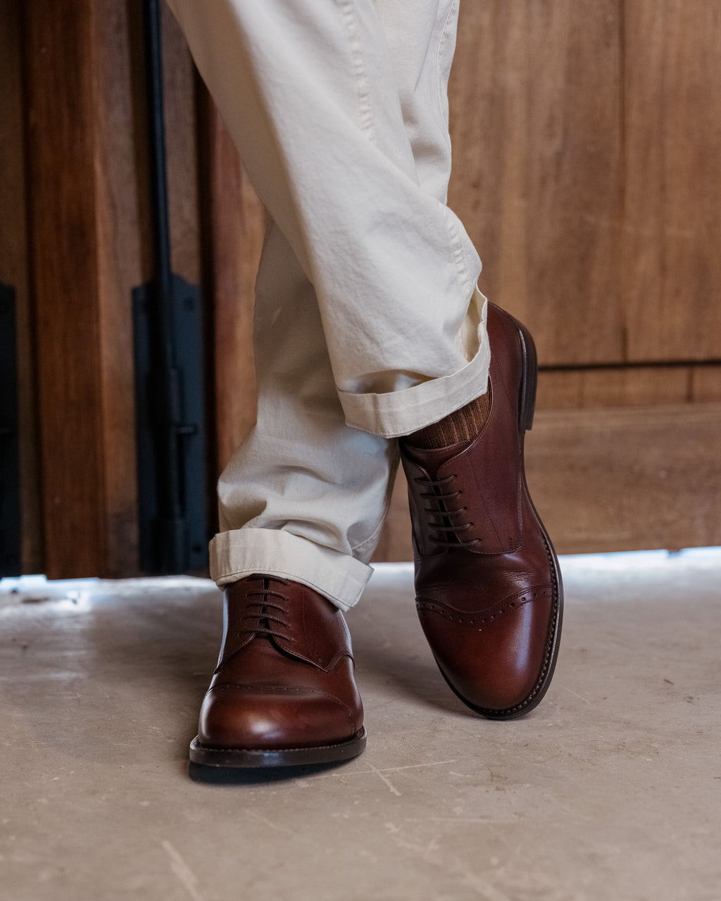 Toe Cap Shoes in Dark Oak, worn with one foot forward in front of a wooden door