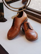 Toe Cap Shoes in English Tan, pair angled together by a window with a brass mirror
