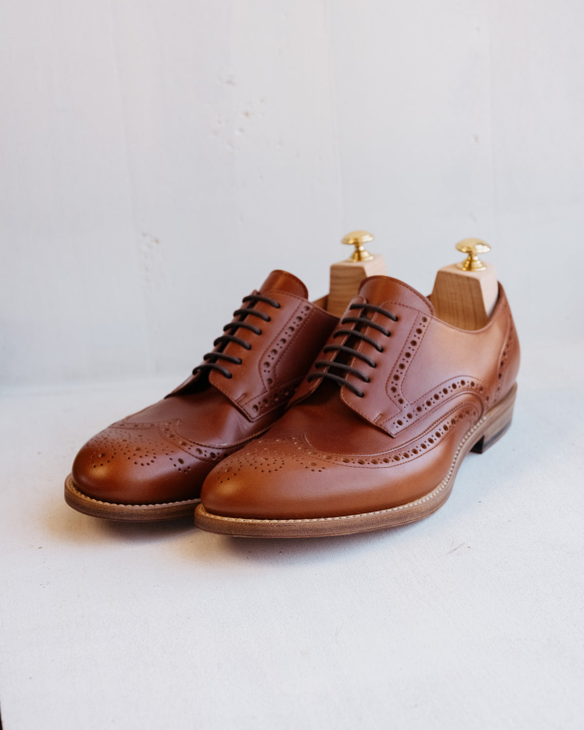Wingtip Shoes in Chestnut, angled front view of pair with shoe trees on a light background