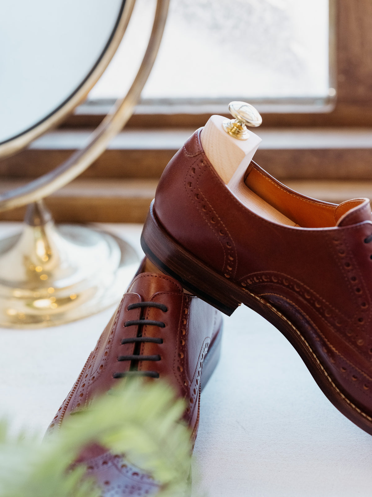 Wingtip Shoes in Chestnut, close-up of heel with shoe tree beside a brass mirror