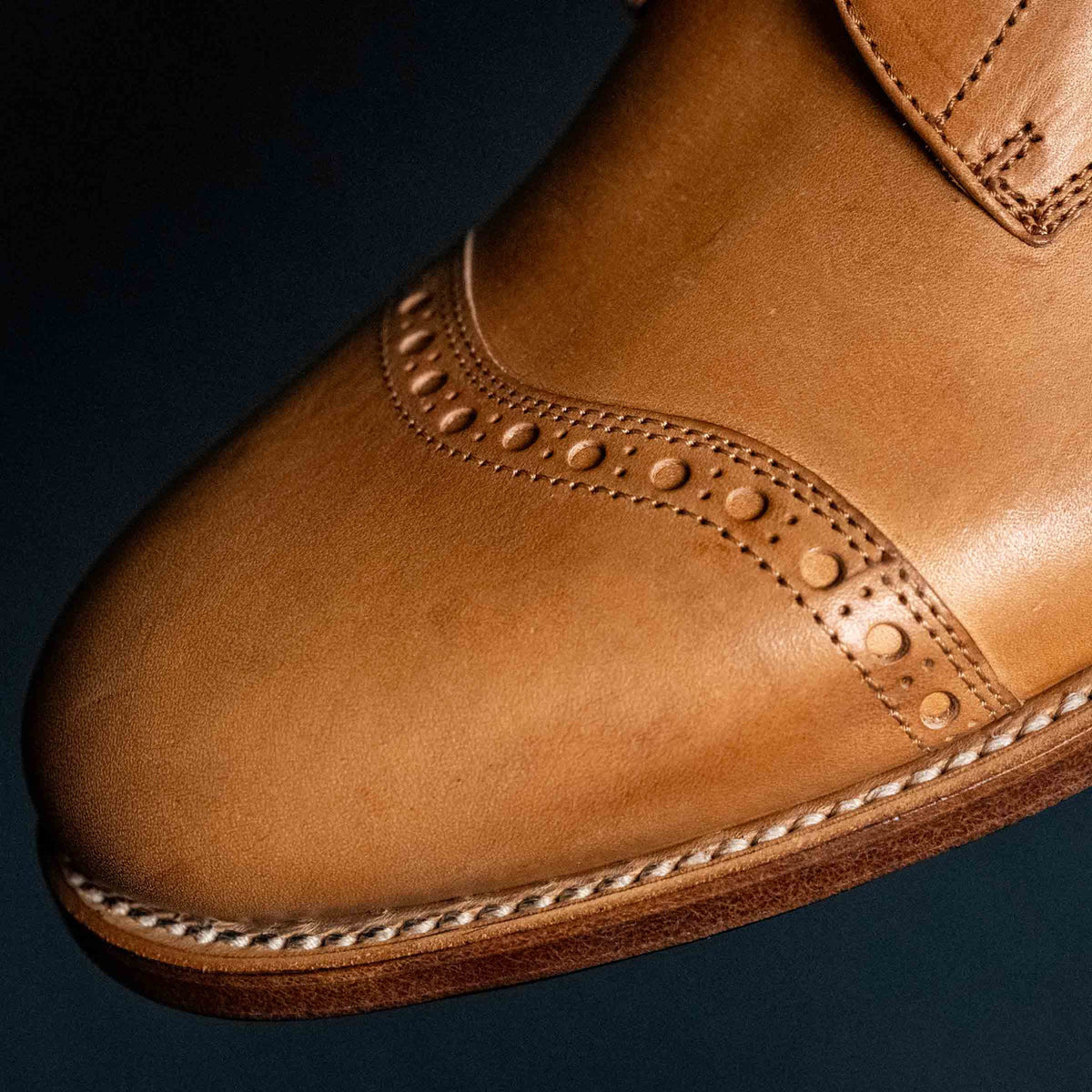 Close detail of the brogued toe cap and welt stitching on a high quality English tan leather Officer's Boot
