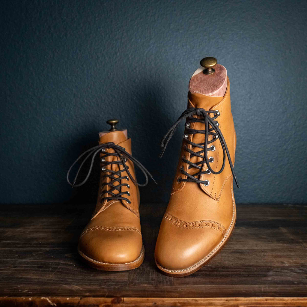 Officer's Boot in English Tan, pair with dark laces and shoe trees, one boot raised on a stand