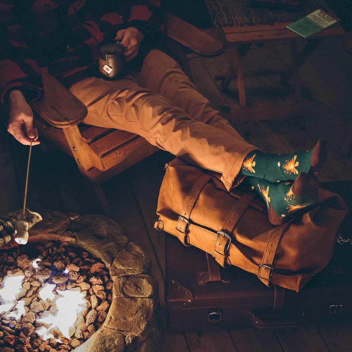 24" Waterbag in tan, used as a footrest by a fire pit while someone roasts a marshmallow