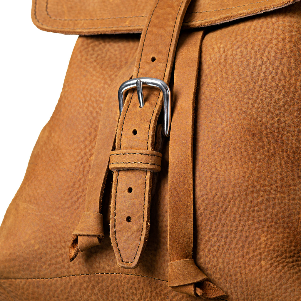 12" Drawstring Backpack in Tobacco, close-up of front flap strap, buckle and drawstring ends