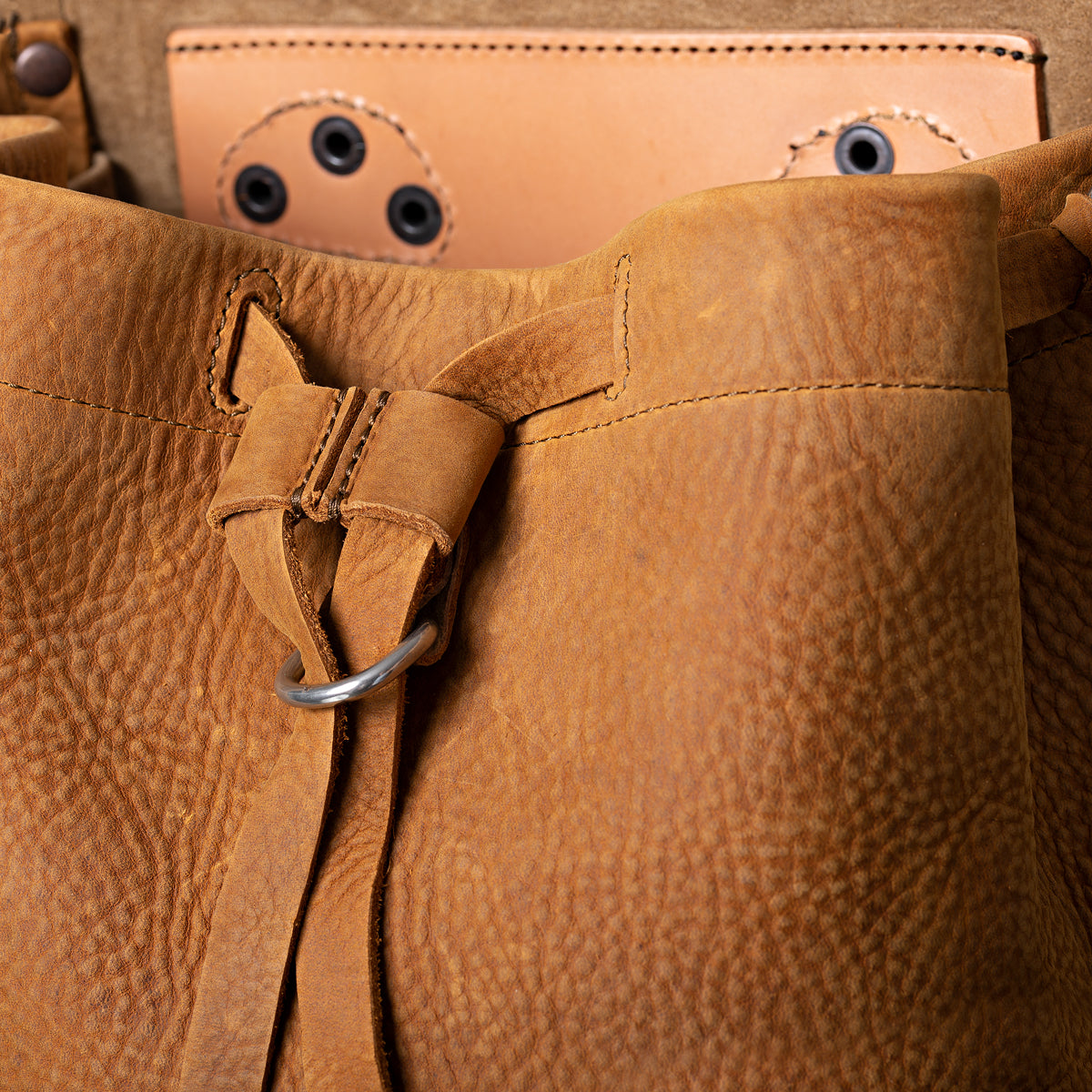 12" Drawstring Backpack in Tobacco, close-up of drawstring tie and ring below the open flap