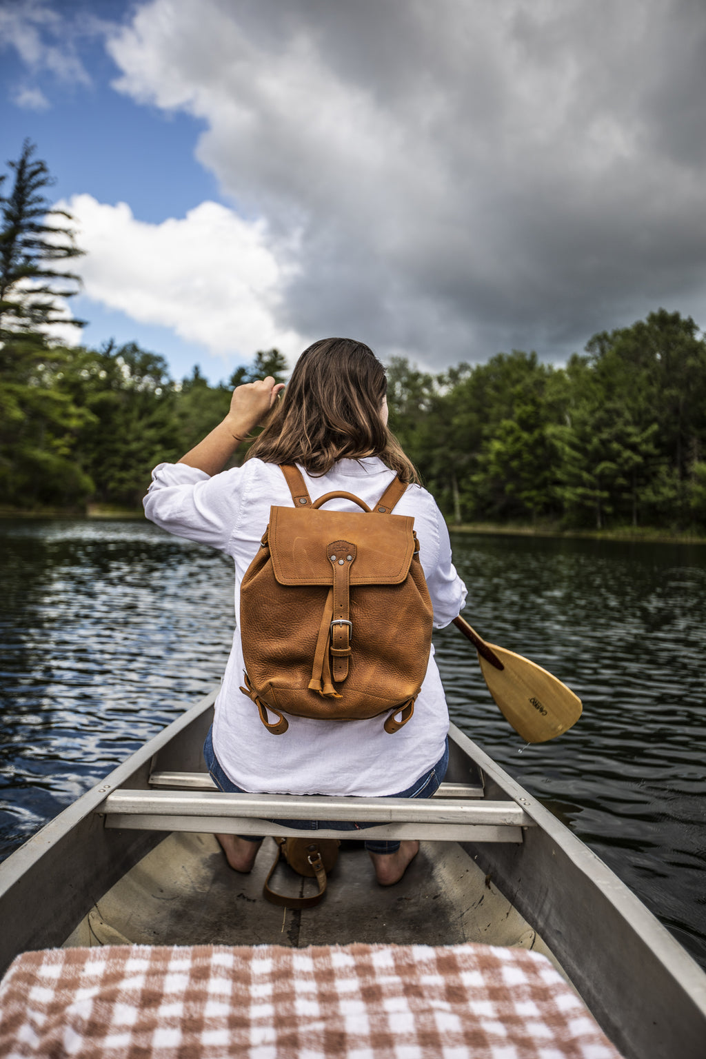 12" Drawstring Backpack in Tobacco, worn by a woman paddling a canoe on a lake