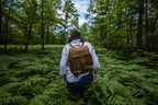 12" Drawstring Backpack in Tobacco, worn by a woman walking through ferns in a forest