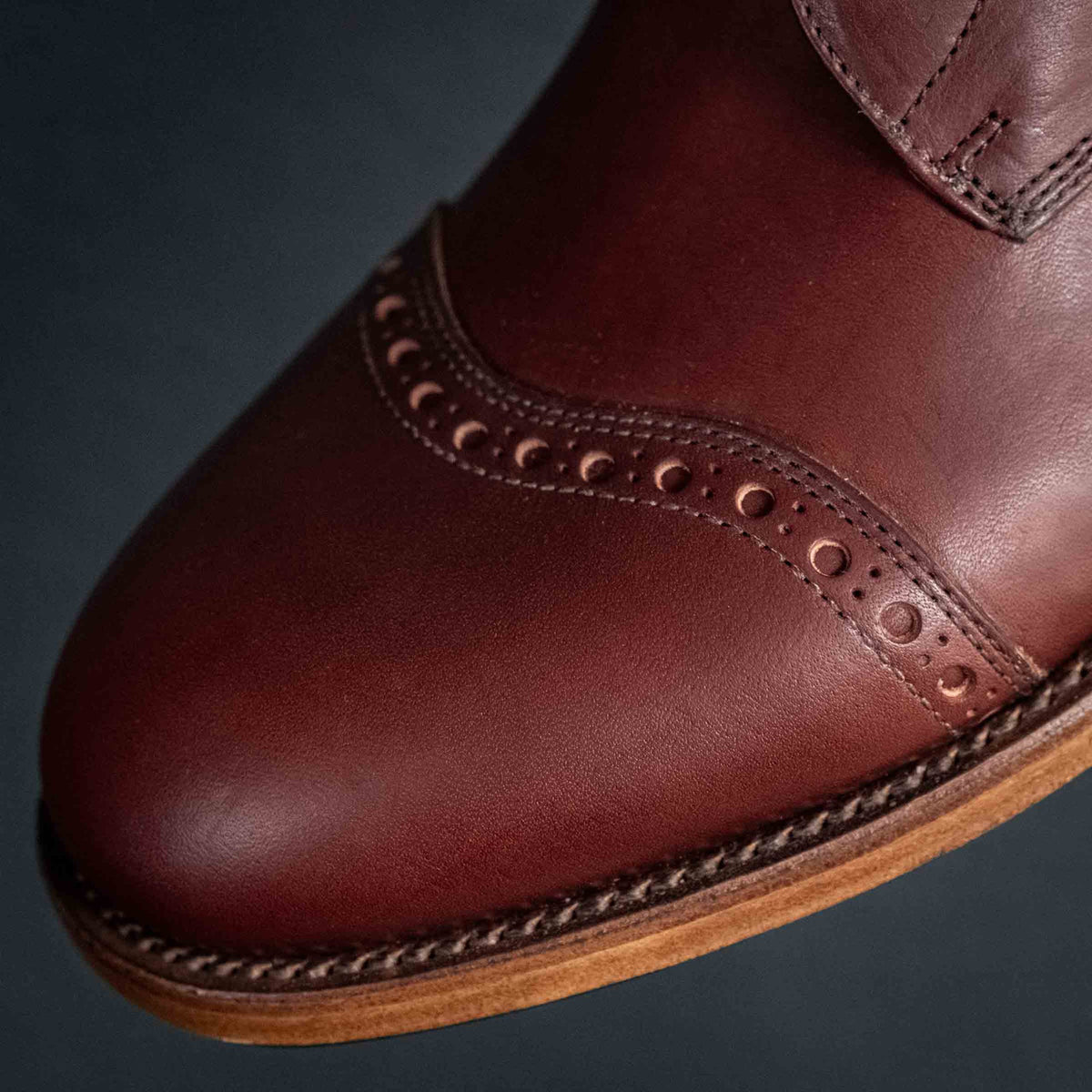 Officer Boot in Oxblood, angled close-up of toe cap brogue detail and stitched welt
