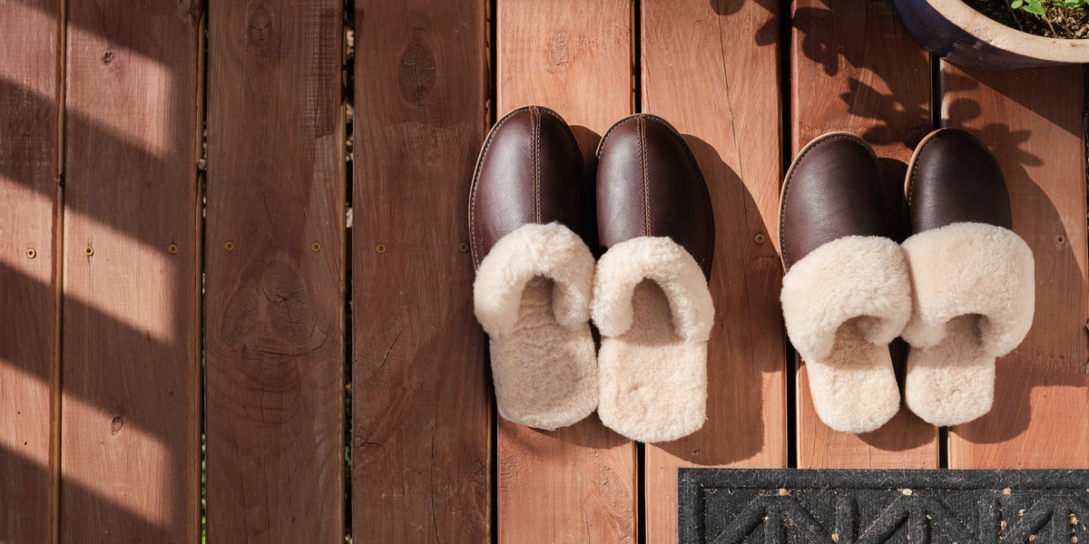 Sheepskin Slippers - New Design for men and women in Dark Coffee Brown, top view of two pairs side by side on a wood deck