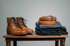 Officer's Boot in English Tan beside a coiled tan leather belt on folded jeans on a wooden stool