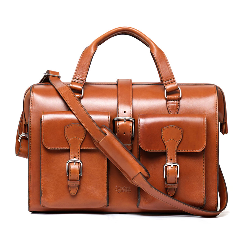 Tan leather briefcase with two buckled front pockets, rolled top handles and a shoulder strap.