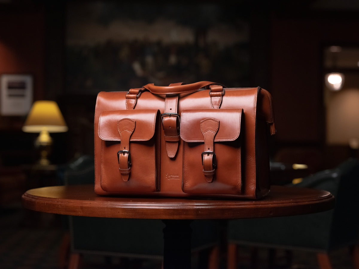 Blackstone Barrister Briefcase in English Tan, front view on a round table in a dim lounge