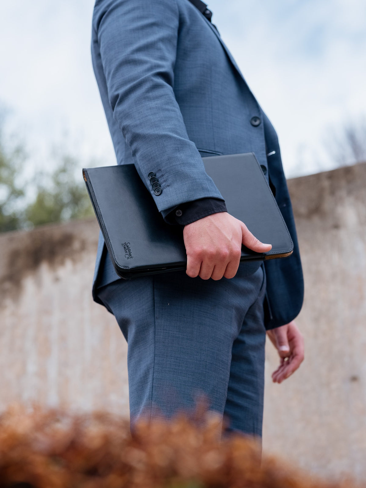 C.S. Lewis Medium Portfolio in Raven Black carried under the arm by a man in a blue suit