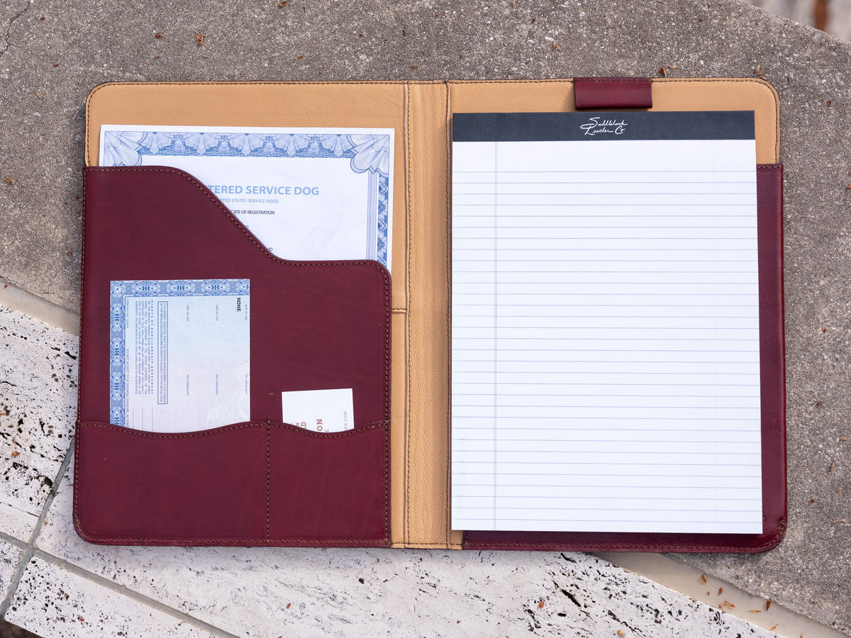 C.S. Lewis Medium Portfolio in Oxblood, open on stone showing the goatskin lining, document pockets and a legal pad