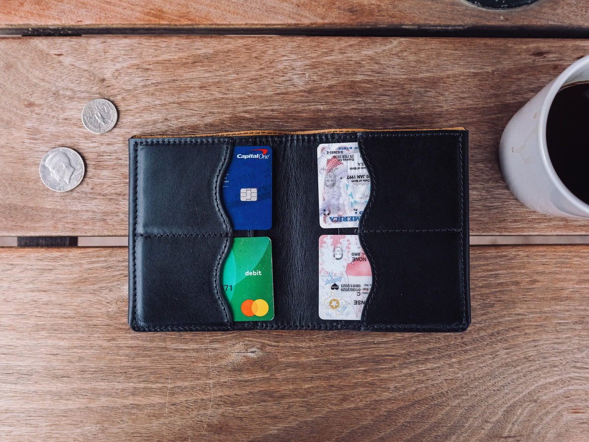 Large Bifold Wallet-Silverback in Raven Black, top view open with cards in four slots beside coins and coffee