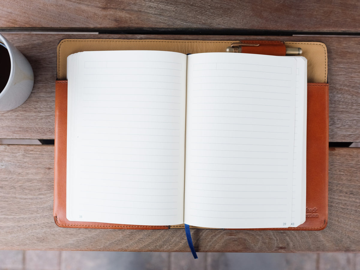 J.R.R. Tolkien Journal Cover in English Tan, top view open with a blank notebook and pen on a wood table