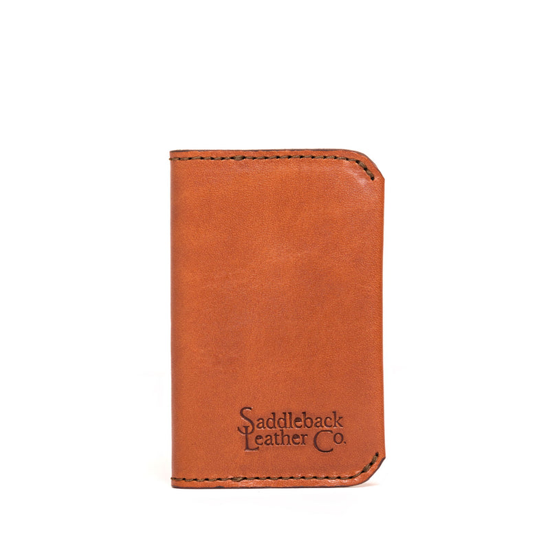 Small closed tan leather business card holder with rounded corners and dark edge stitching.