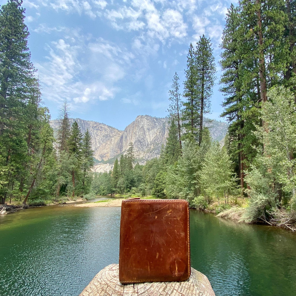 Large Bifold Wallet in Tan, well-worn wallet standing on a log by a mountain river