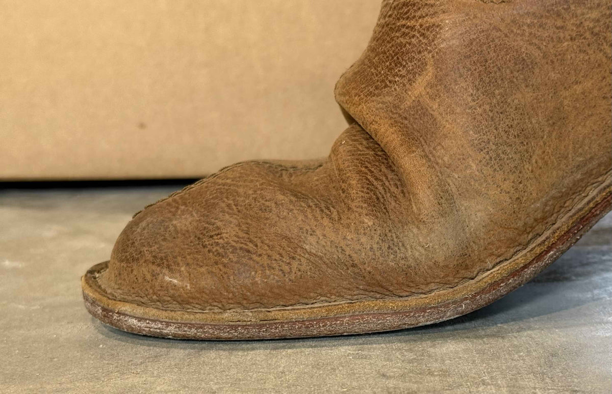 Tan leather barefoot minimalist slip-on shoe flexing at the toe to show its flexible sole