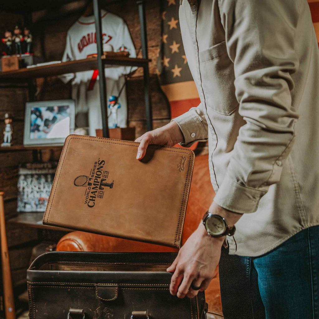 Leather Portfolio - Texas Rangers World Series in Tobacco being placed into a bag in a room full of baseball memorabilia