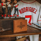 Leather Bifold Wallet - Texas Rangers World Series in Tobacco on a shelf with baseball bobbleheads and a jersey behind