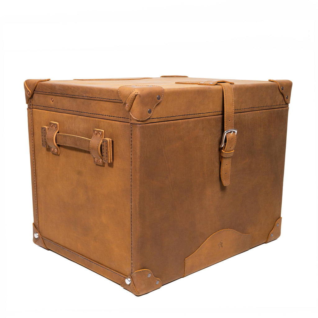 Leather Small Trunk in Tobacco, closed angled view with buckled strap, side handle and leather corner guards