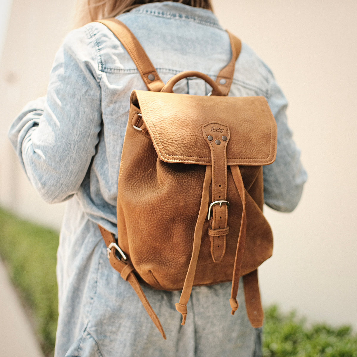 12" Drawstring Backpack in Tobacco, worn over a denim jacket, back view