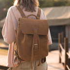 12" Drawstring Backpack in Tobacco, worn by a woman walking on a wooden boardwalk